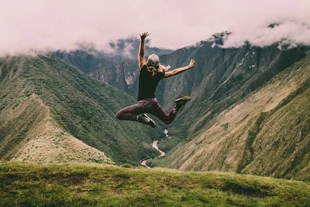 Sur un paysage de montagne, une femme saute de joie.